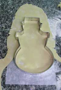 raw biscuit dough cutting a snowman cookie out