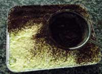 dusting cocao powder on the tiramisu dessert