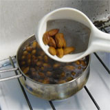 taking the almonds out of the boiling water with a sieve